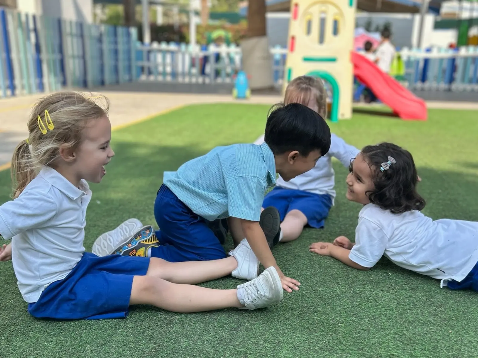 Pre School children playing together on the grass at BPS