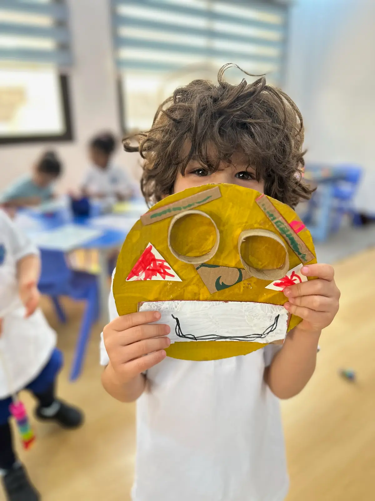 A Reception child at BPS holding up a mask they have painted