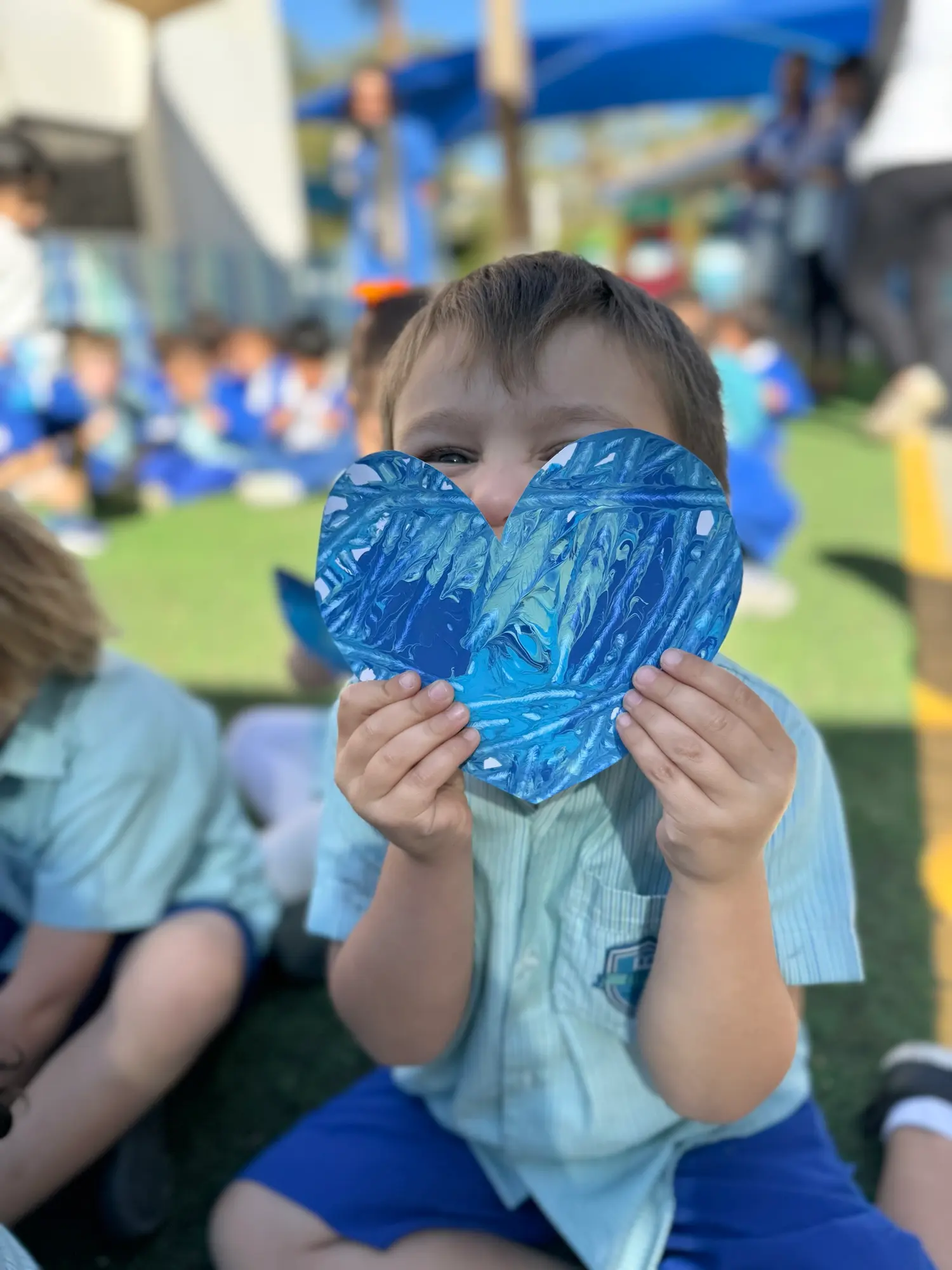 A BPS child holding up a blue paper heart they have made